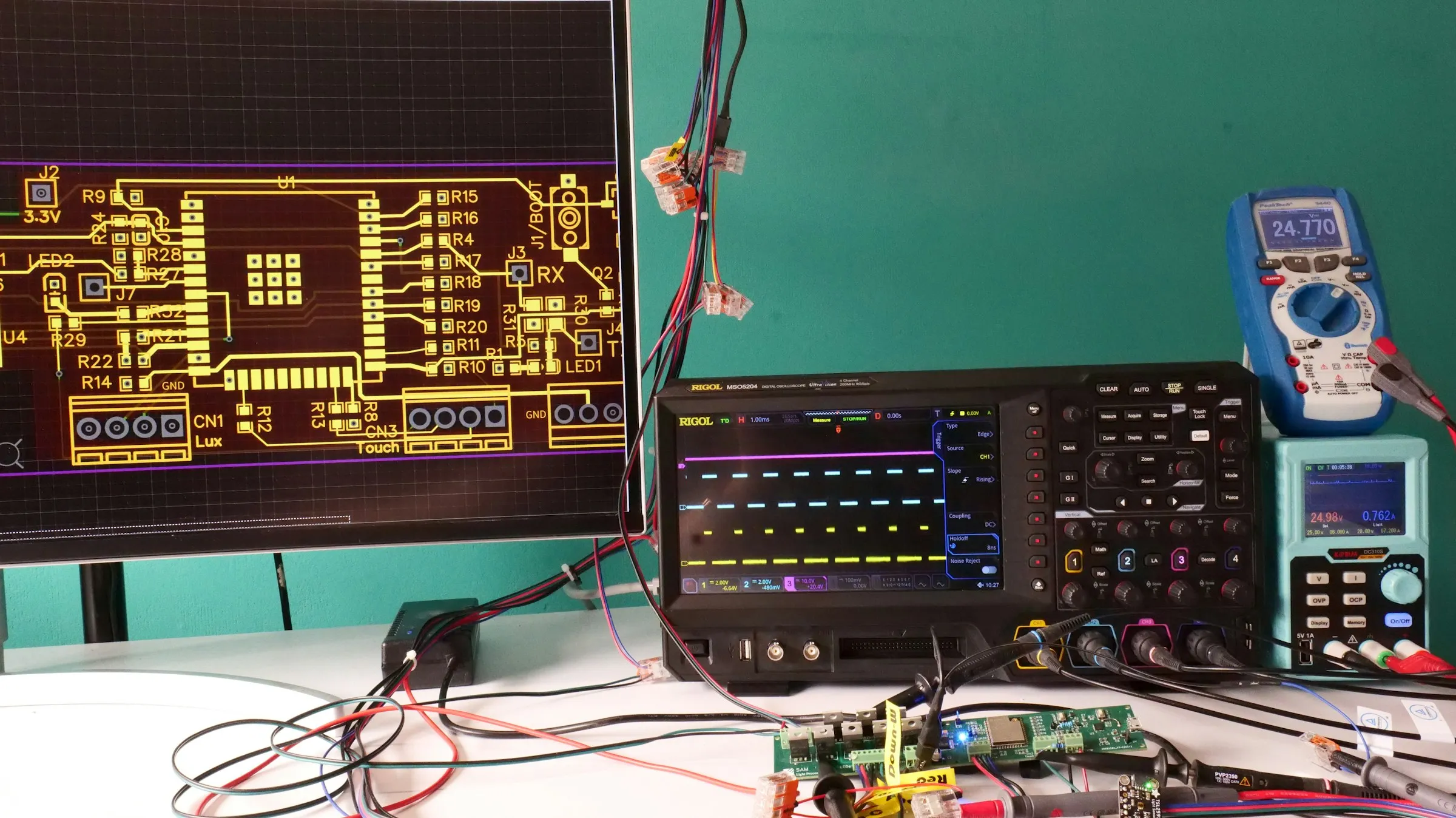 Electronics engineering workbench with a circuit design display, test equipment and prototype board.